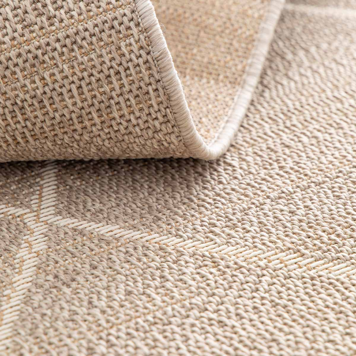 Close-up van een beige vloerkleed met opgetilde rand, textuur zichtbaar.