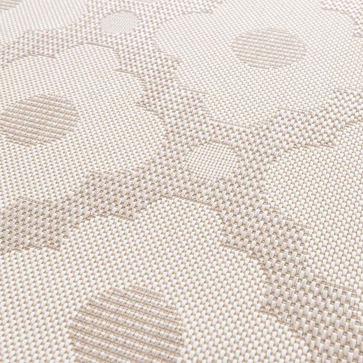 Beige vloerkleed met geometrisch patroon van cirkels en zigzags.