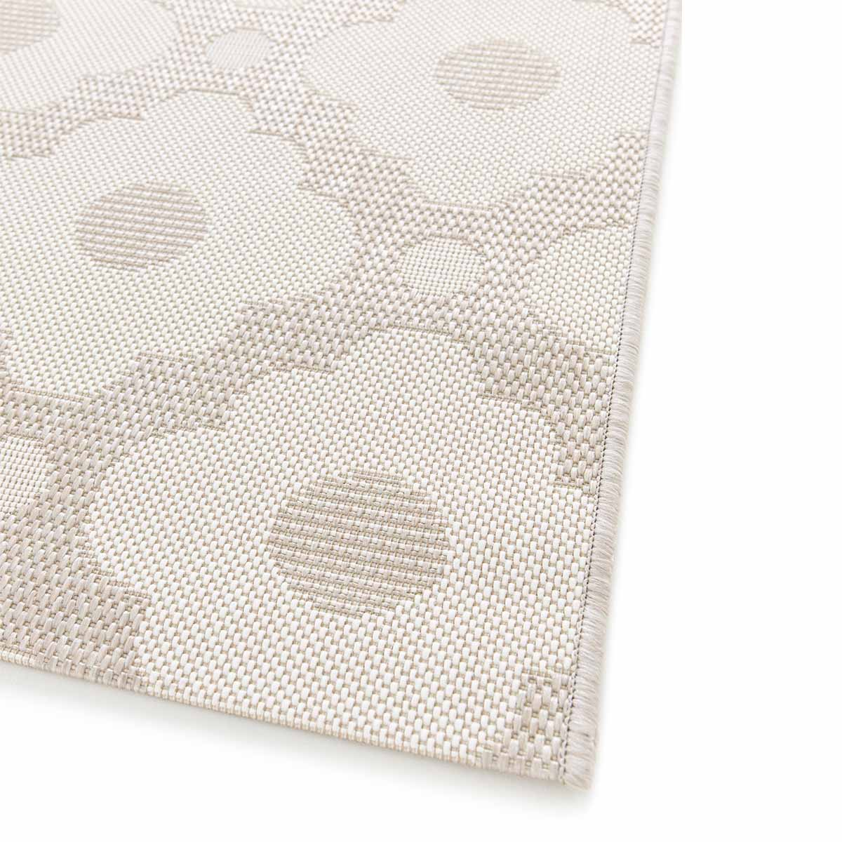Beige vloerkleed met een abstract bloempatroon in een lichtere tint.