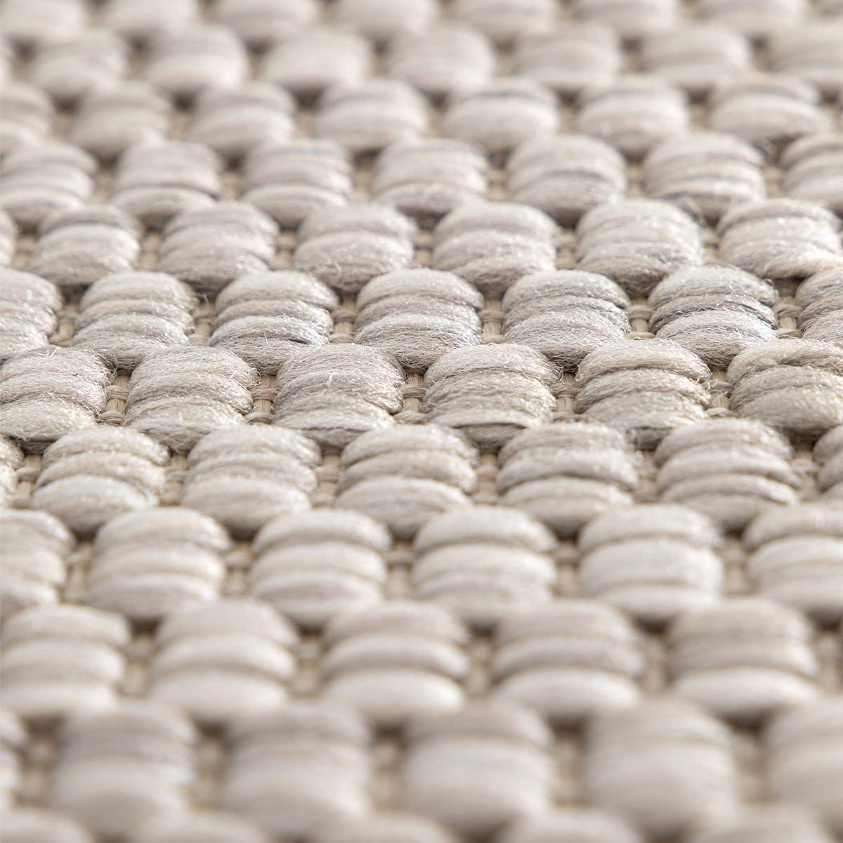 Close-up van een beige vloerkleed met een geweven, getextureerd patroon.
