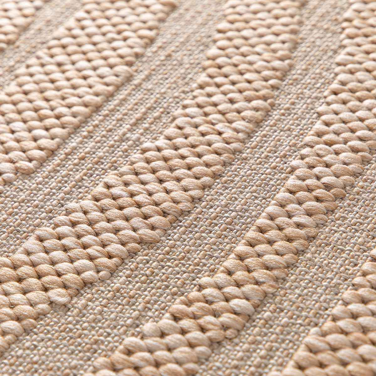 Close-up van een beige vloerkleed met een verticale streep textuur.