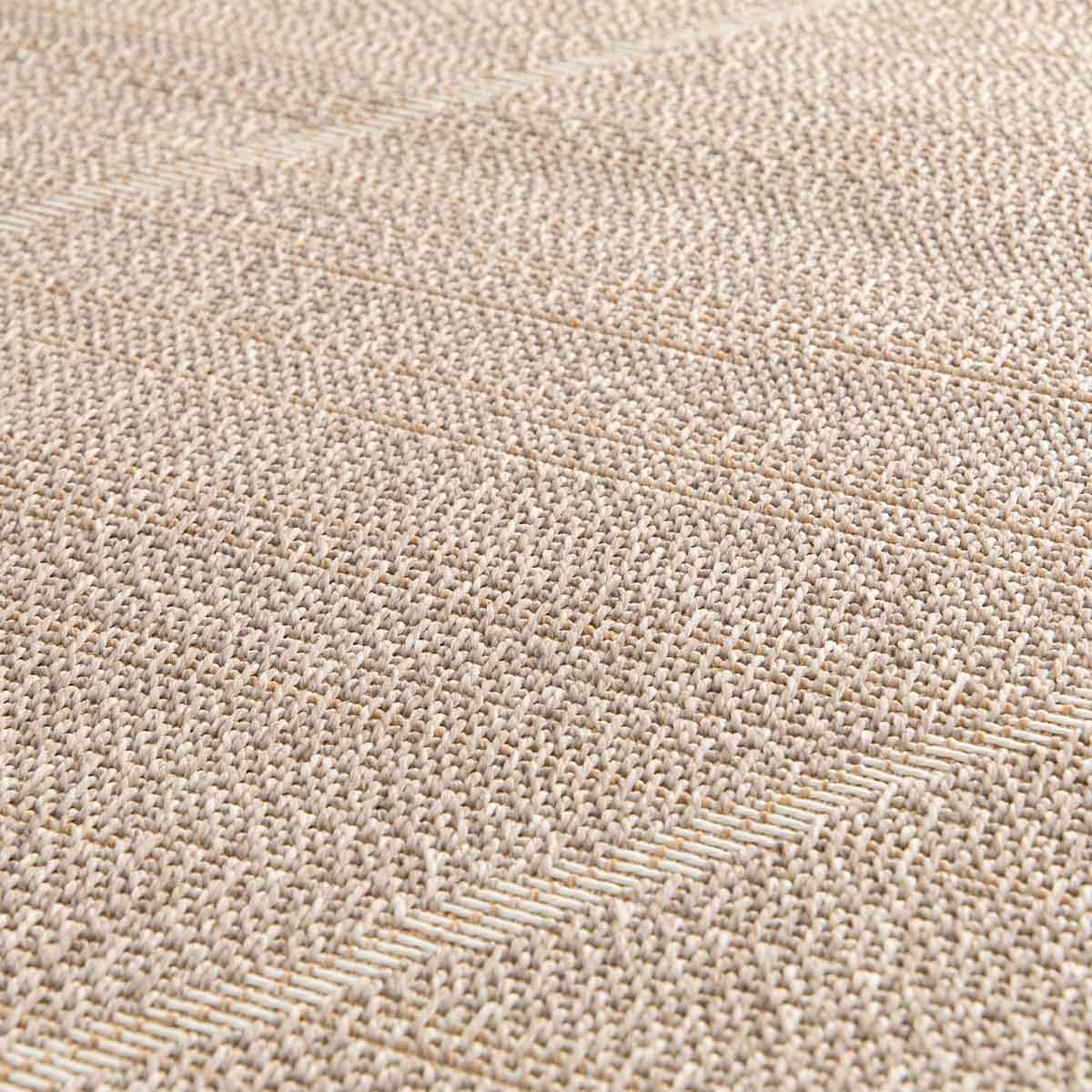 Close-up van een beige tapijt met visgraatpatroon.