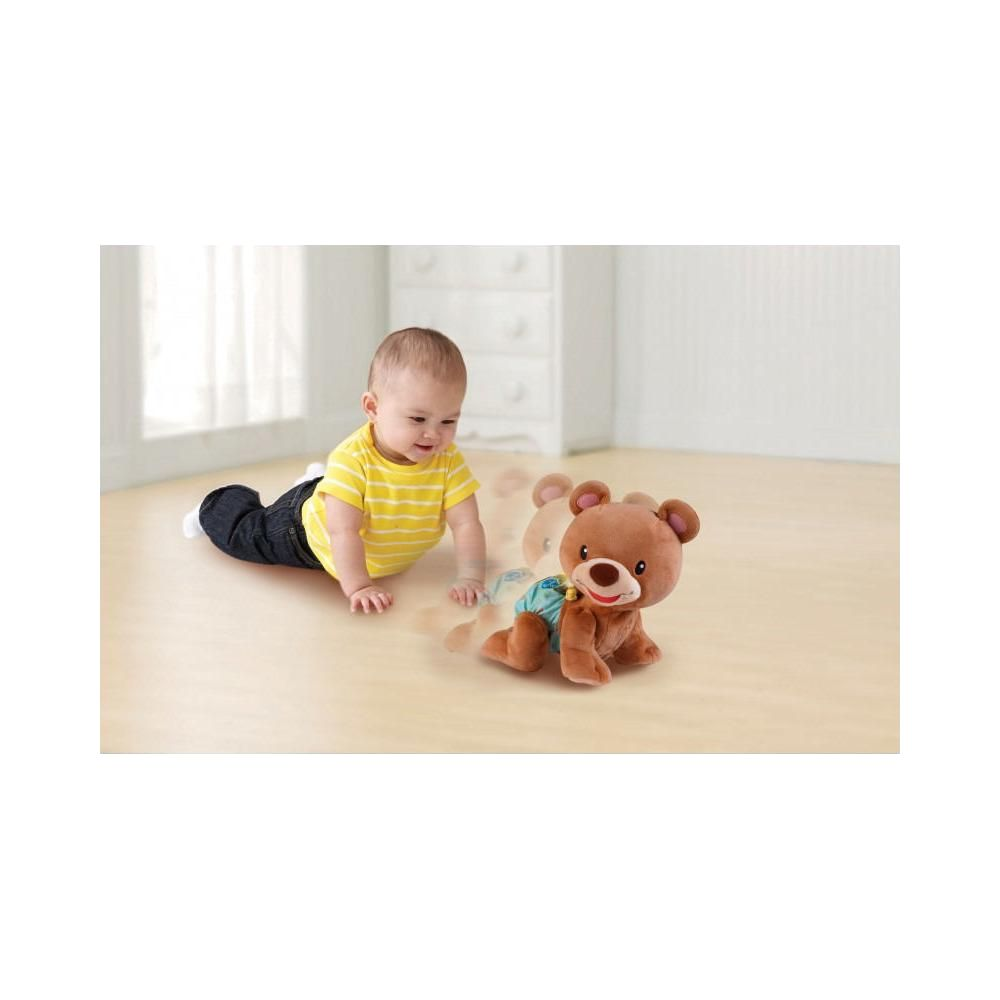 Ein Baby krabbelt auf einem Holzboden neben einem Spielzeugbären.