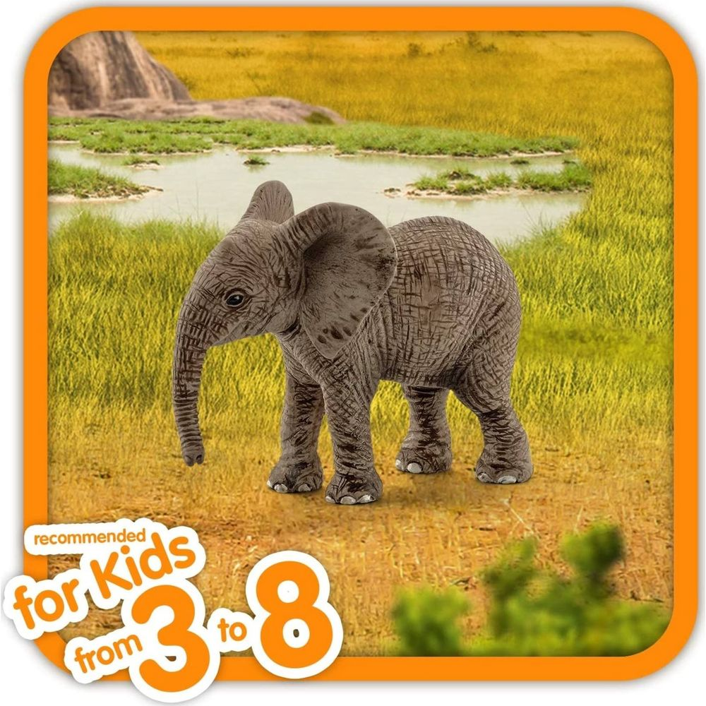 Un cucciolo di elefante si trova nella savana vicino a uno specchio d'acqua.