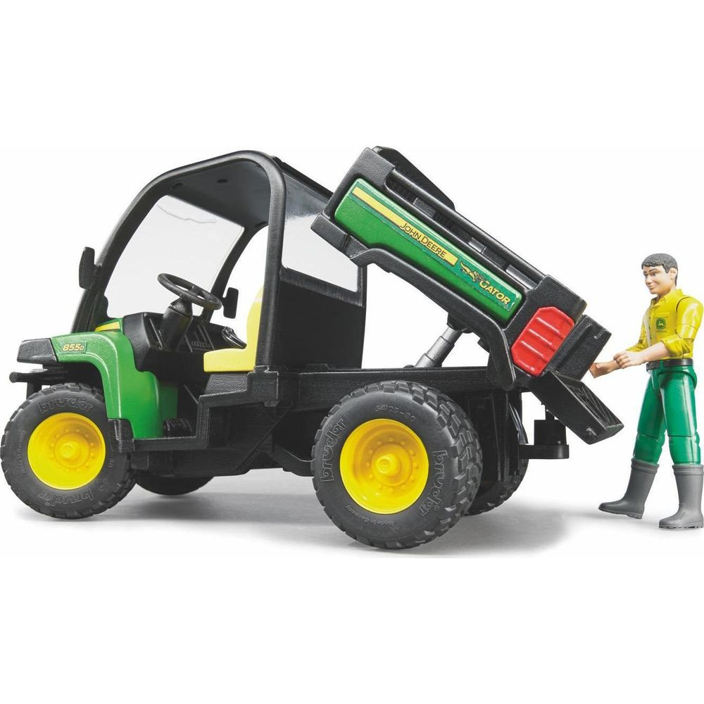 Zabawkowy John Deere Gator z podniesioną skrzynią, obok stoi figurka kierowcy.