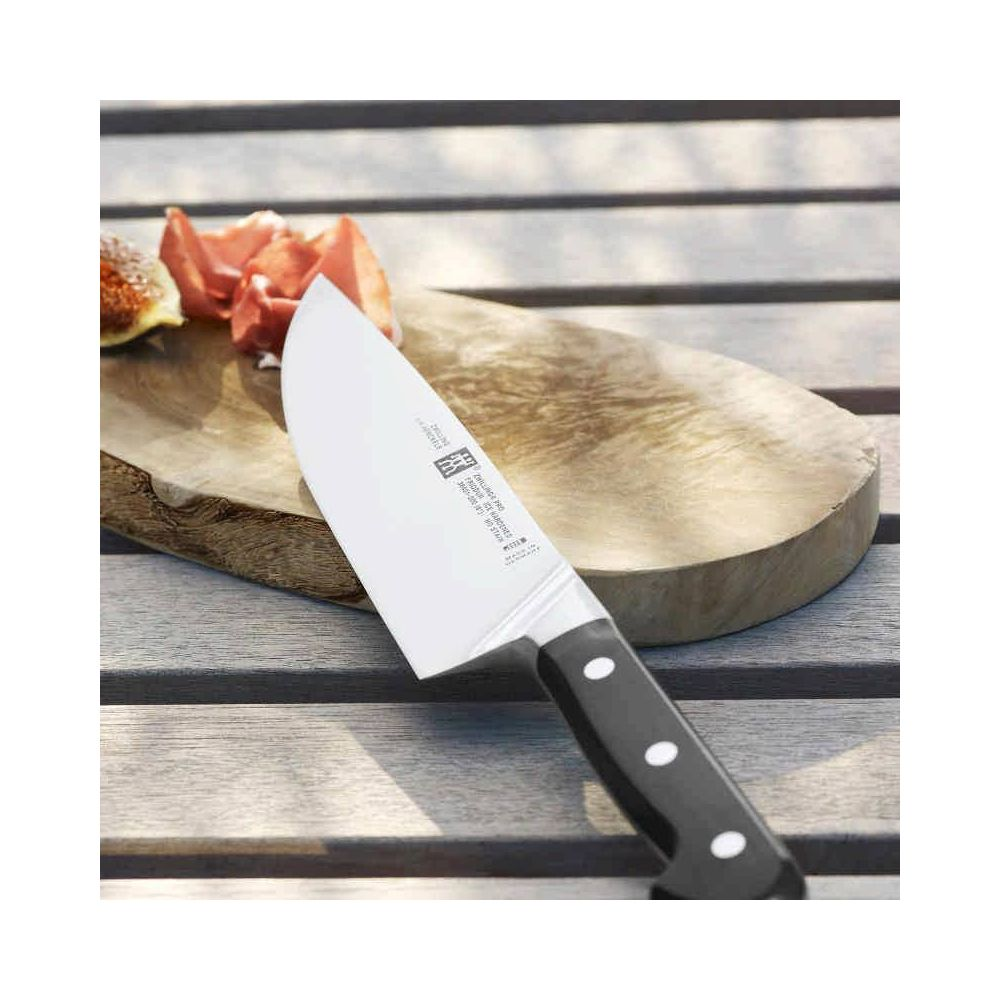 Nóż szefa kuchni z czarną rączką leży na drewnianej desce obok fig.