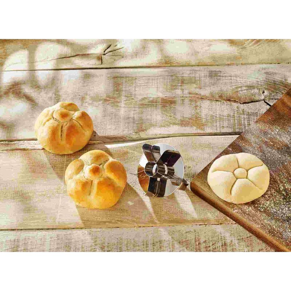 Zwei gebackene Brötchen, ein Ausstecher und ein roher Brötchenteig.