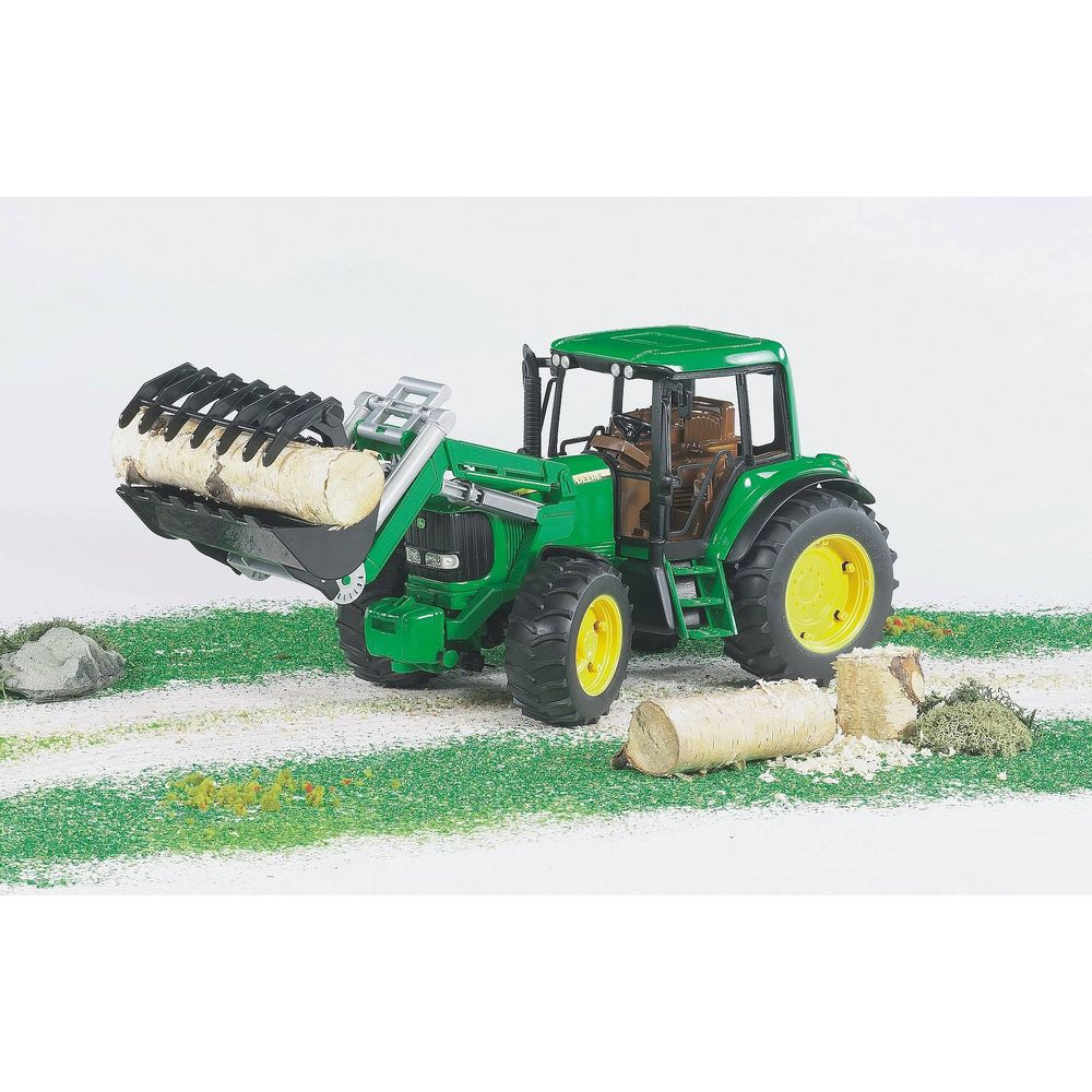 Zielony traktor zabawkowa z ładowaczem czołowym przewożący kłody.