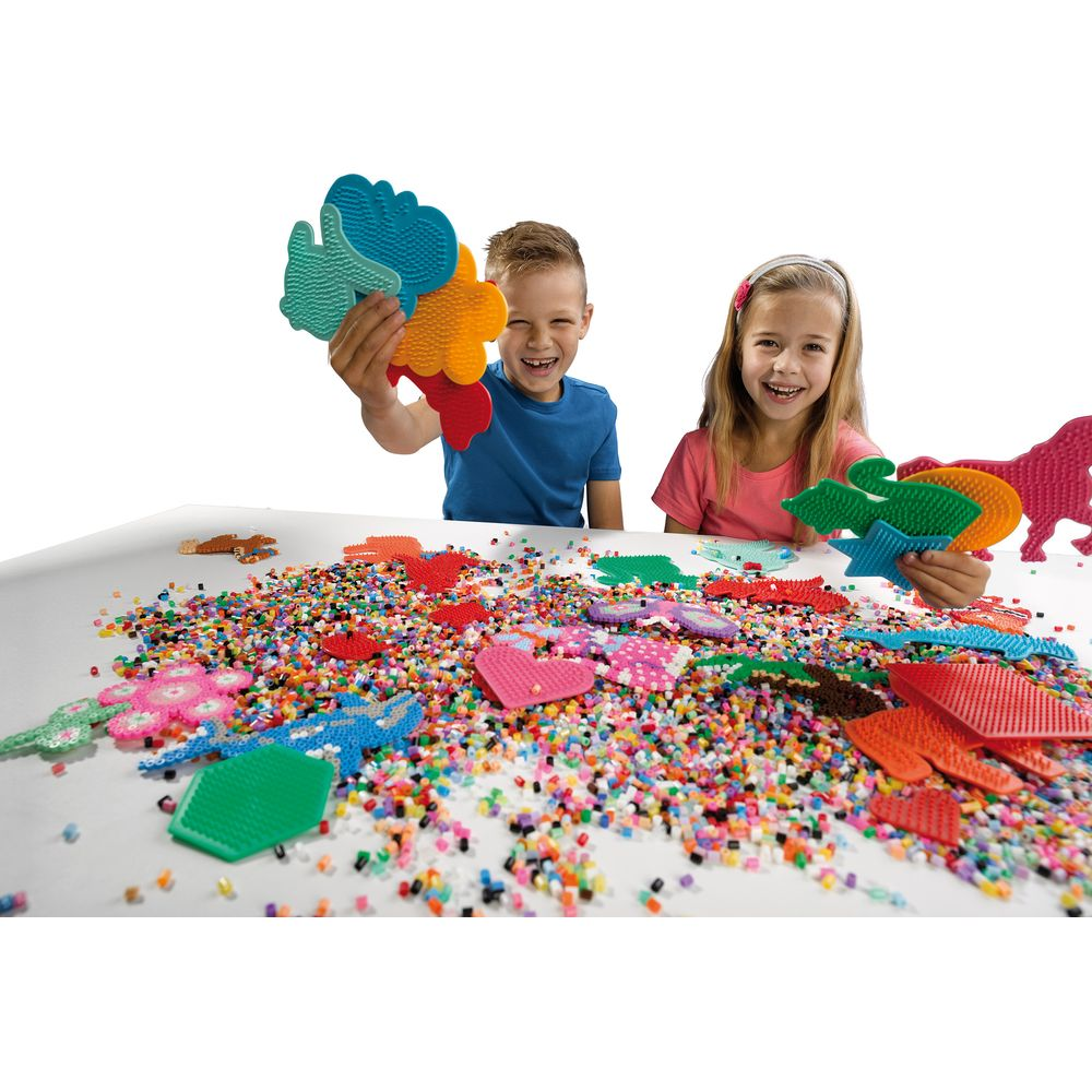 Niños jugando con cuentas y formas de colores sobre una mesa.