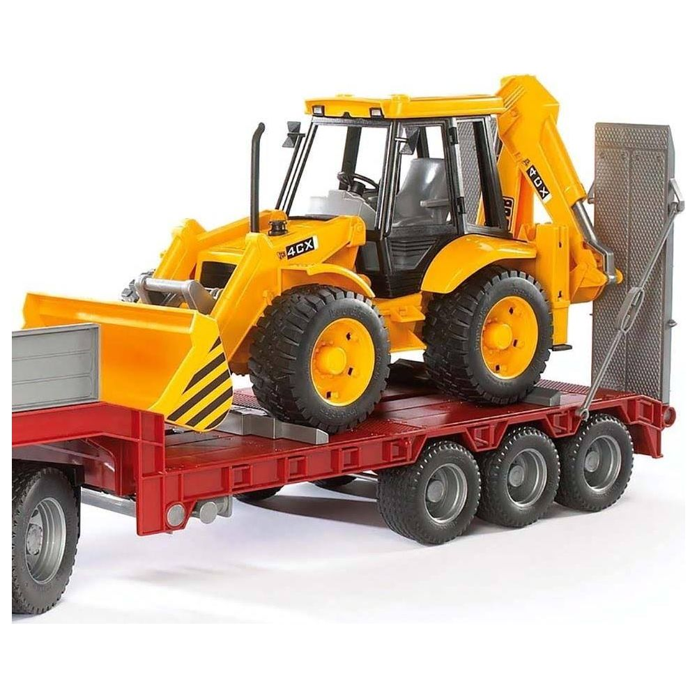 Żółta koparko-ładowarka stoi na czerwonej lawecie z czterema osiami.