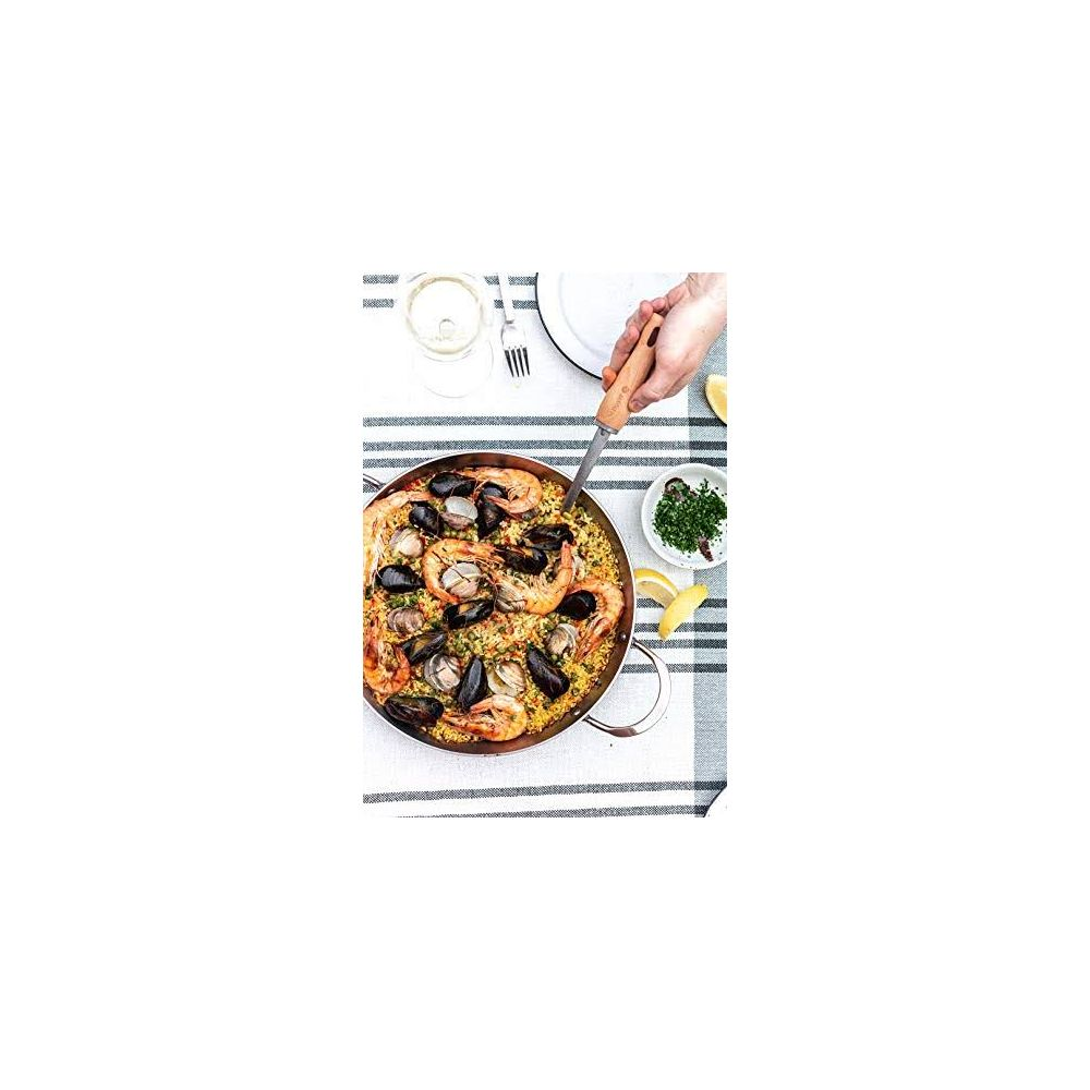 Paella aux crevettes et moules dans une poêle, garnie de citron et de persil.