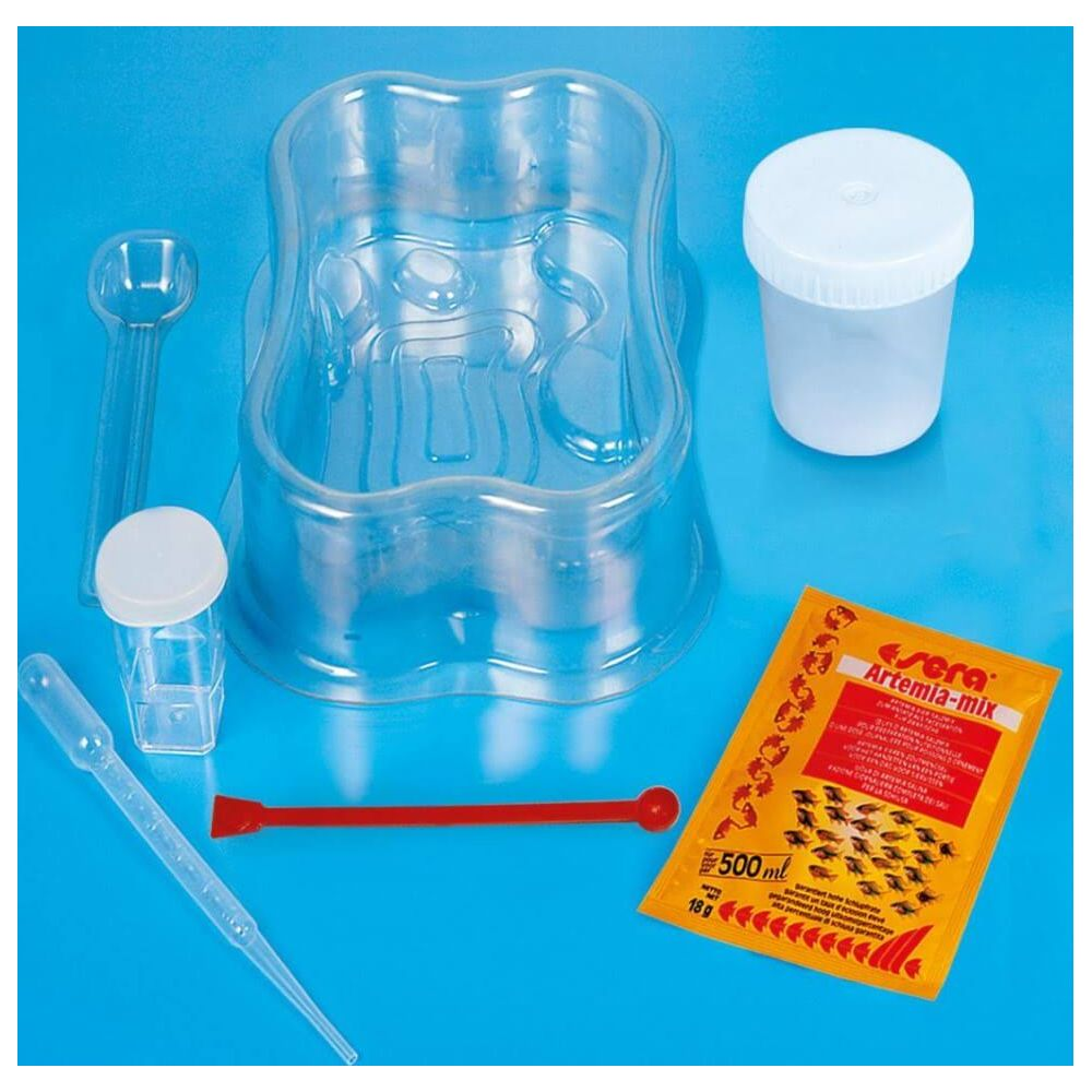 Zestaw do hodowli artemii z pojemnikami, pipetą, łyżką i pokarmem na niebieskim tle.