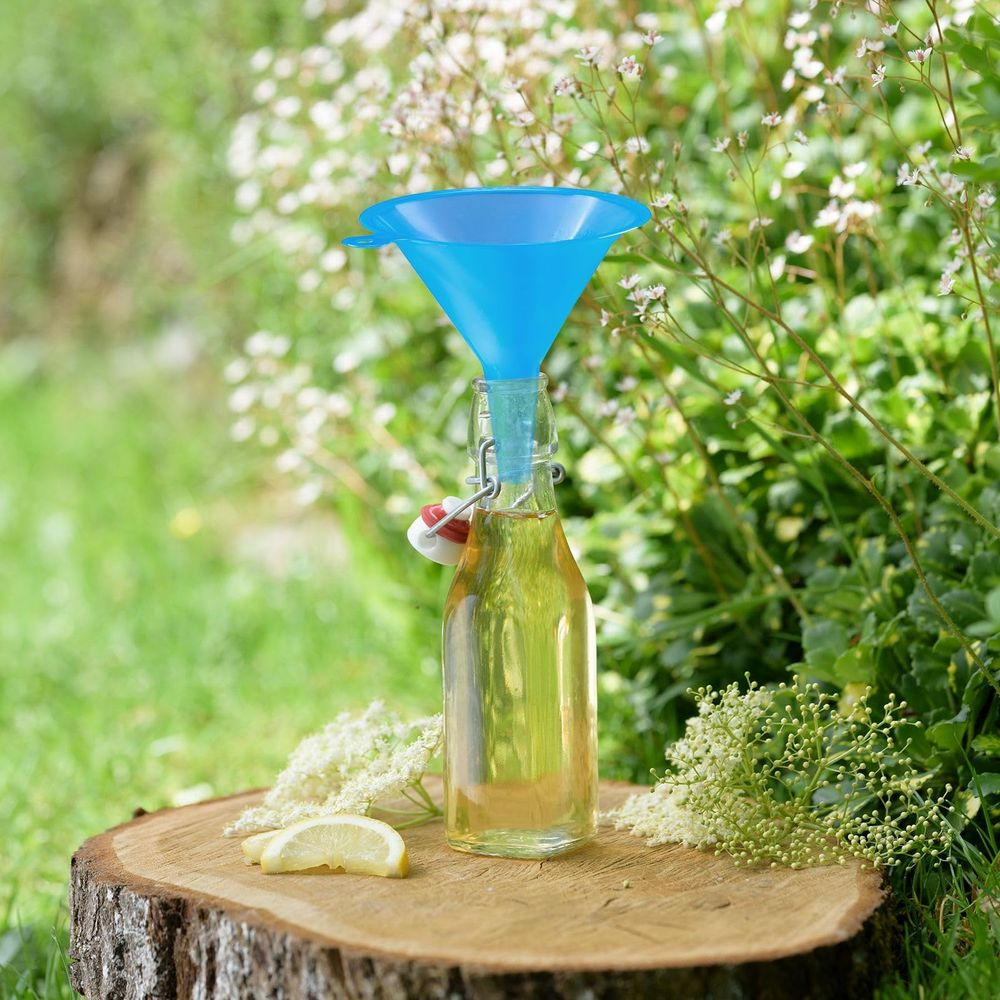 Ein blauer Trichter steckt in einer Glasflasche mit gelber Flüssigkeit, daneben Zitrone.