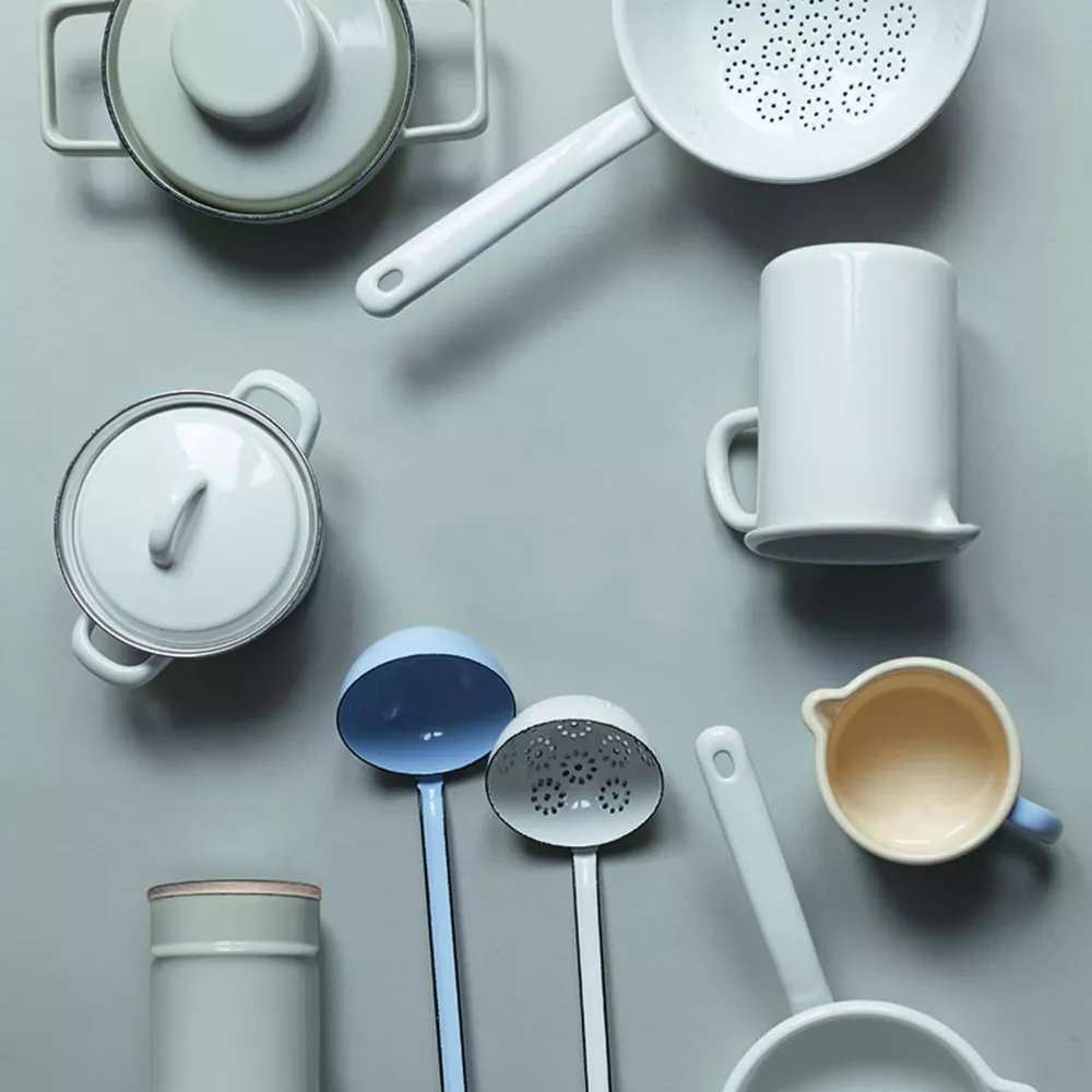 Ustensiles de cuisine blancs et bleu clair, y compris des casseroles, des passoires et des louches.