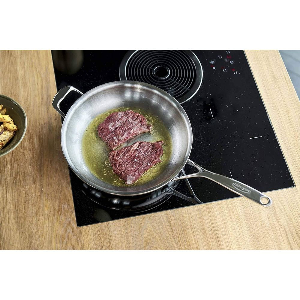 Deux morceaux de viande crue frémissant dans une poêle sur une plaque à induction.