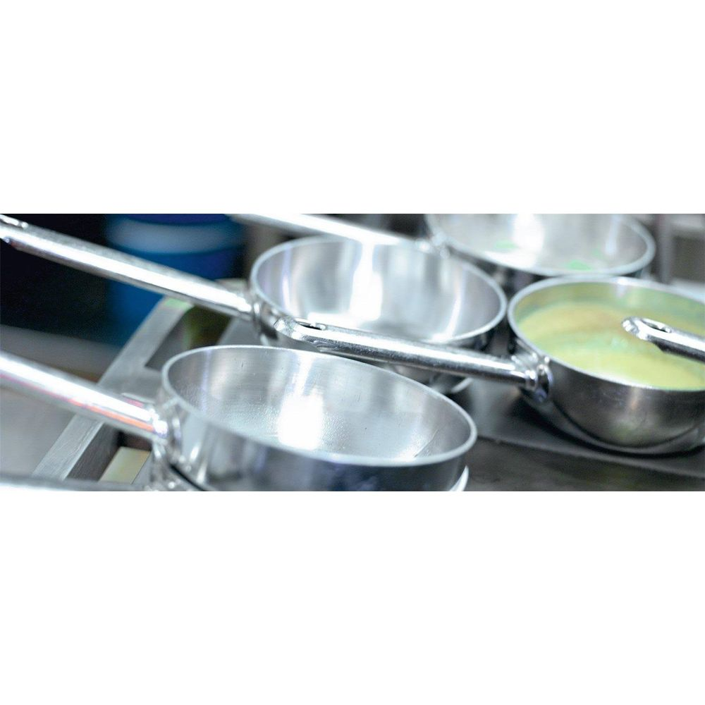 Quatre casseroles en métal brillant avec poignées, une contenant un liquide jaune.