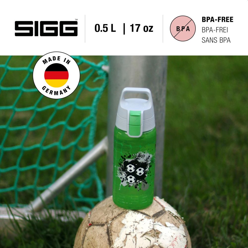 Grüne SIGG-Flasche mit Fußballmotiv auf einem alten Ball, hinter einem Tornetz.