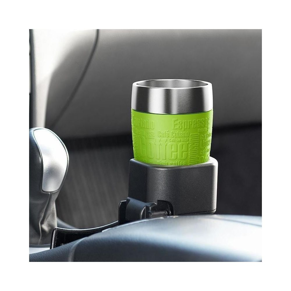 Ein grüner Kaffeebecher mit Text steht in einem Getränkehalter im Auto.