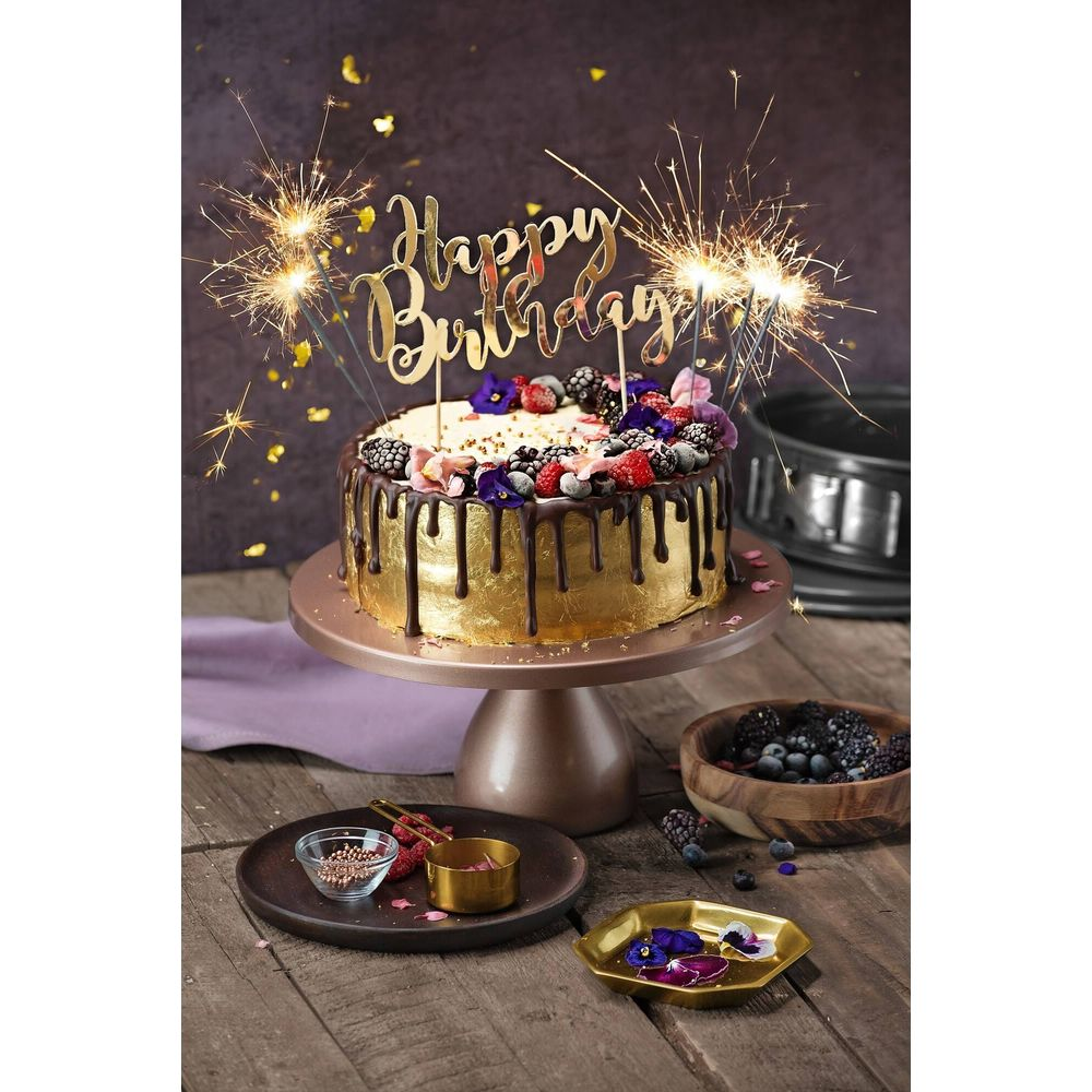 Goldene Geburtstagstorte mit Schokoladenglasur, Beeren, Funken und "Happy Birthday"-Topper.