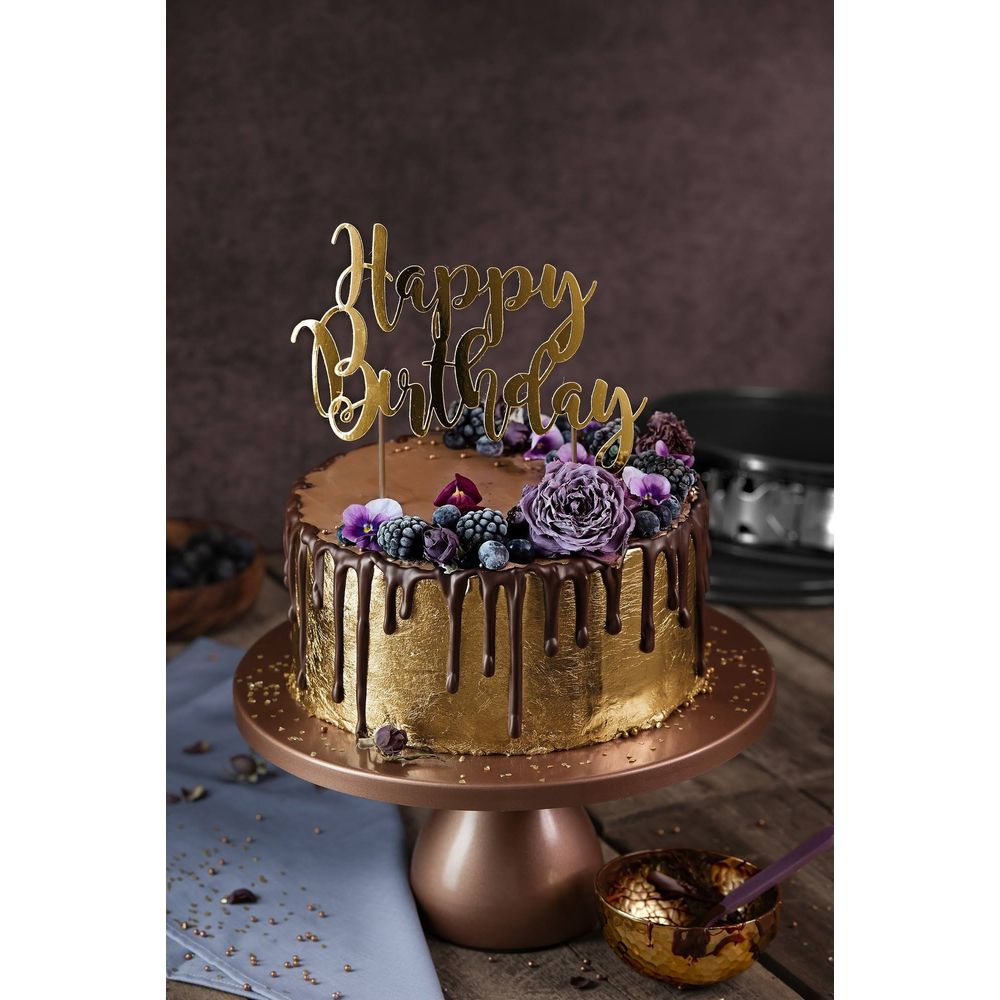 Goldene Geburtstagstorte mit Schokoglasur, Beeren und Blumen.