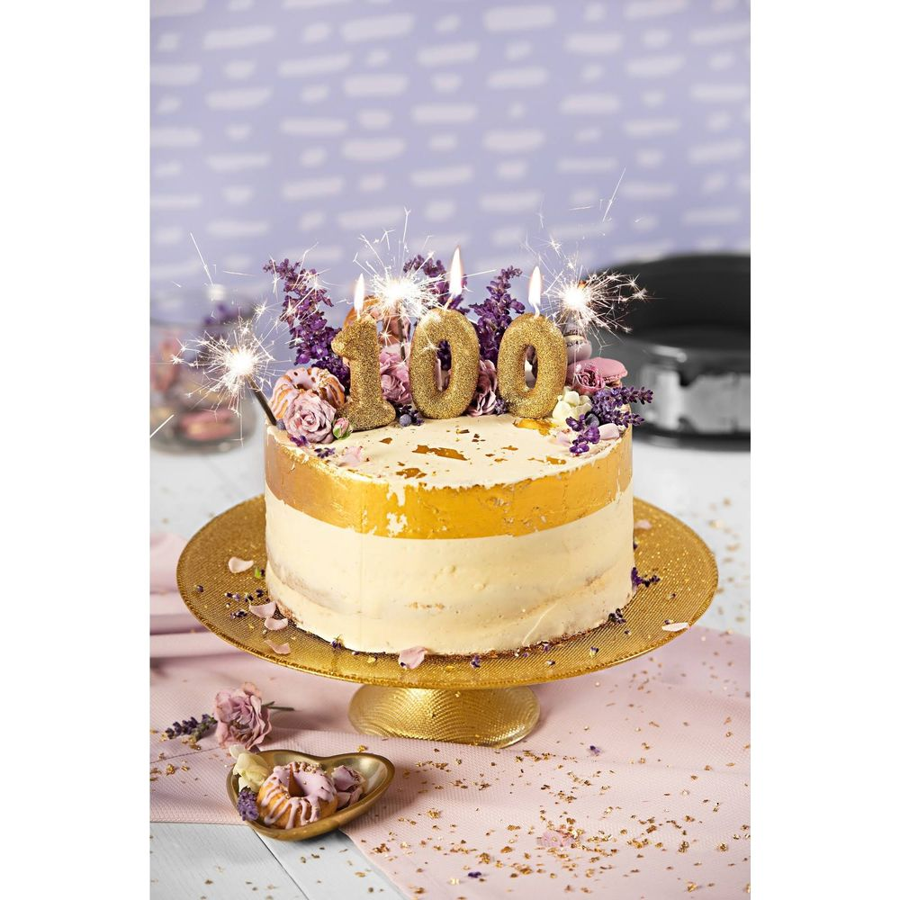 Geburtstagstorte mit 100 Kerzen, Blumen und Wunderkerzen auf goldenem Ständer.