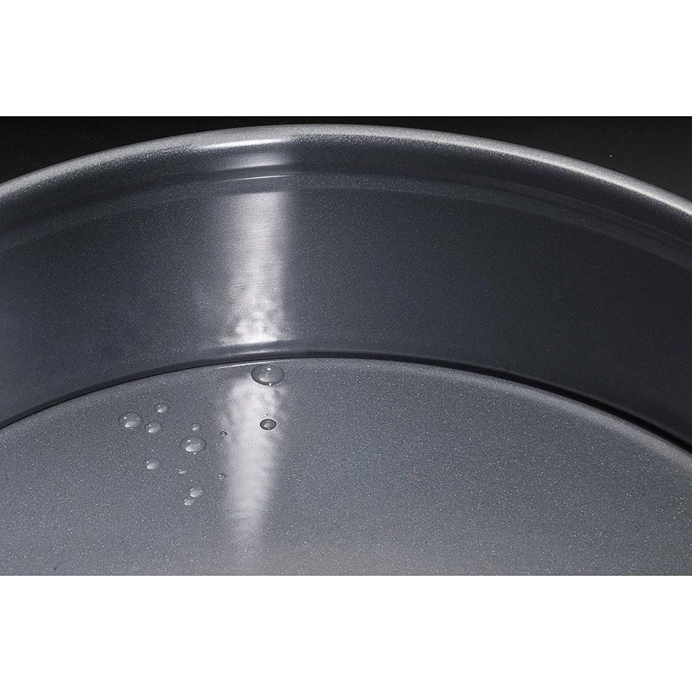 Graue runde Backform mit Wassertropfen auf dem Boden.