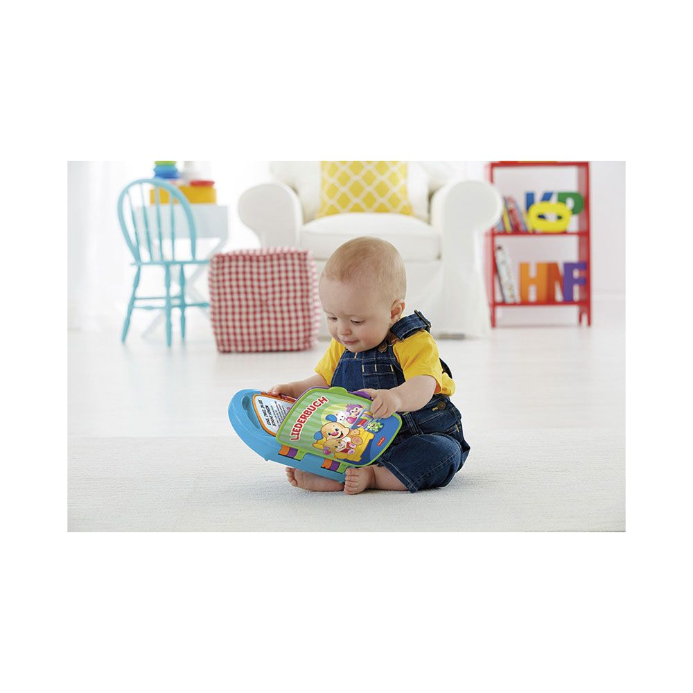 Ein Baby in Latzhosen spielt mit einem bunten Spielzeugbuch.