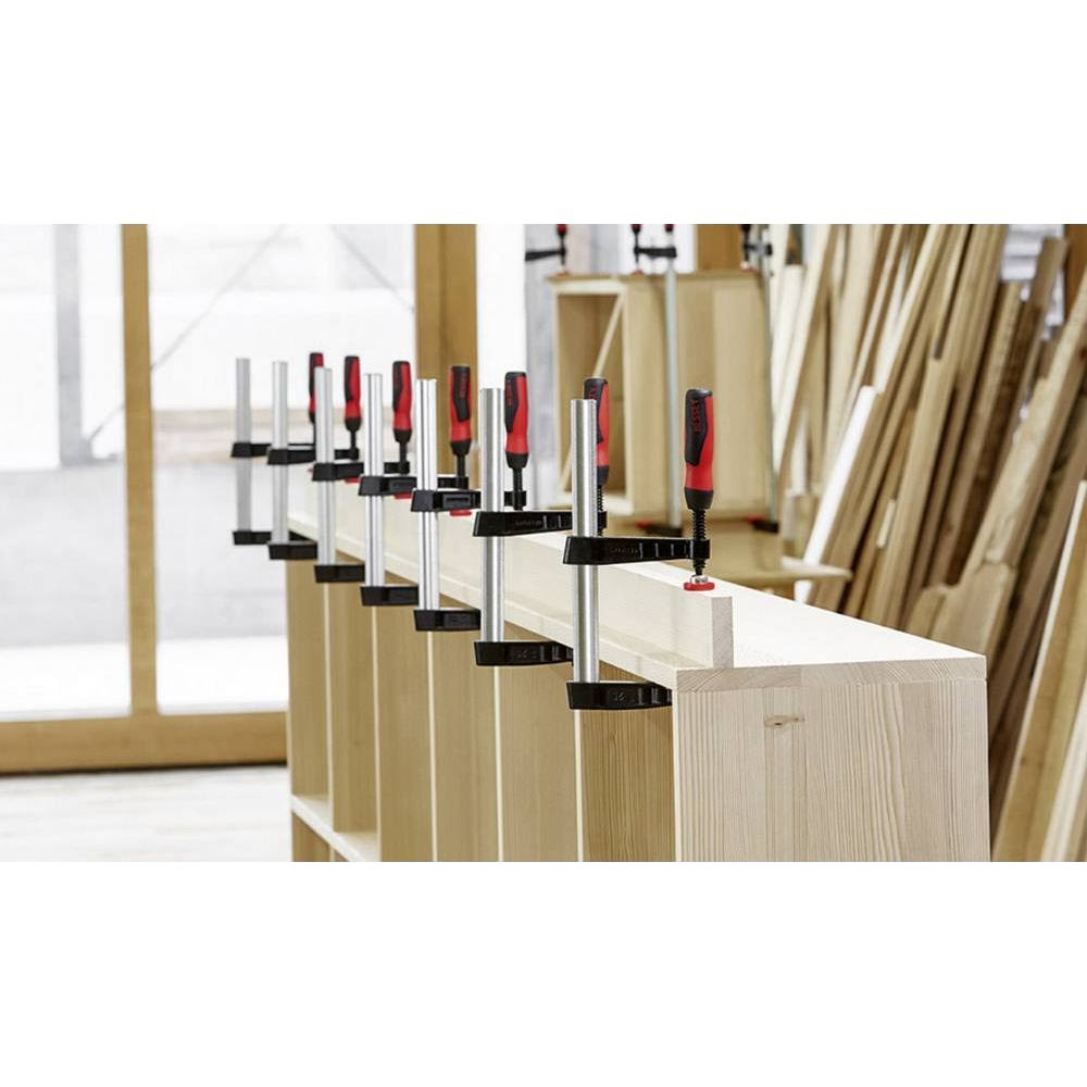 Holzklemmen mit roten Griffen fixieren Holzstücke auf einer Werkbank.
