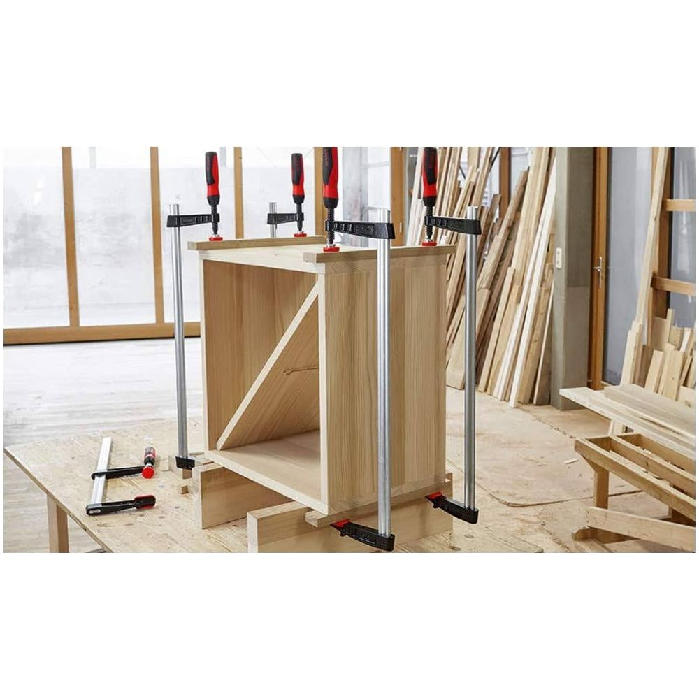 Ein Holzschrank wird mit vier Zwingen auf einem Tisch zusammengehalten.
