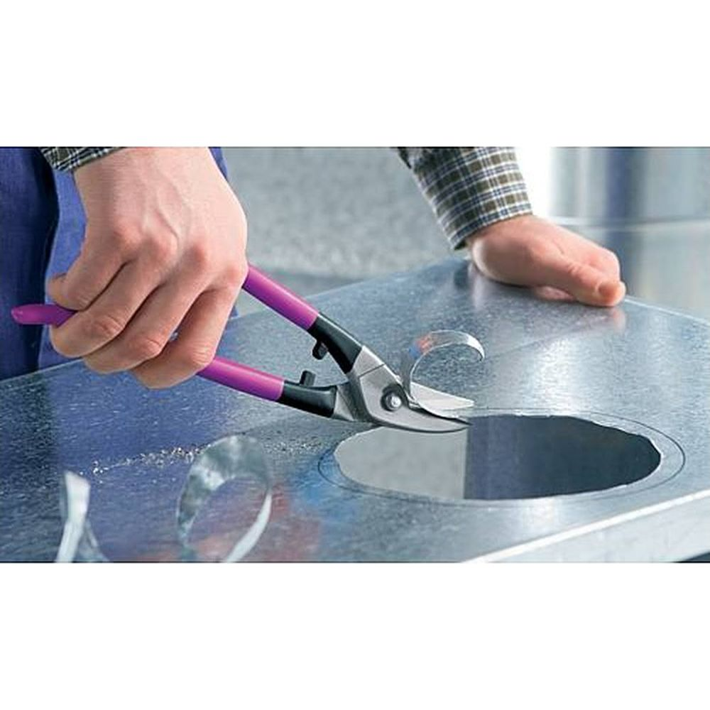 Eine Hand benutzt eine Blechschere mit violetten Griffen, um Metall zu schneiden.