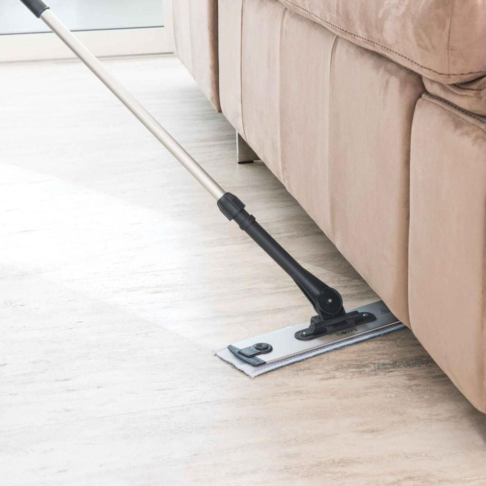 Mop czyści podłogę pod beżową kanapą.