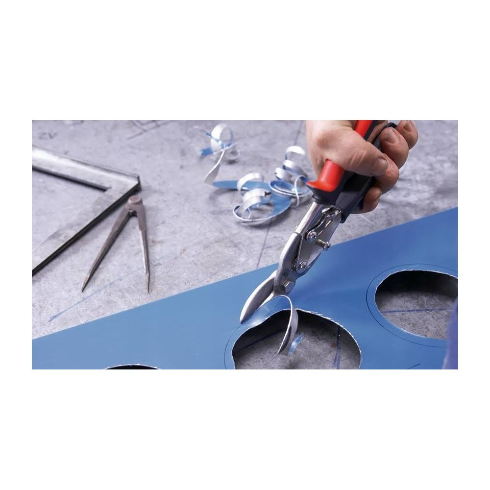 Hand schneidet blaues Blech mit Schere, Metallspäne liegen herum.