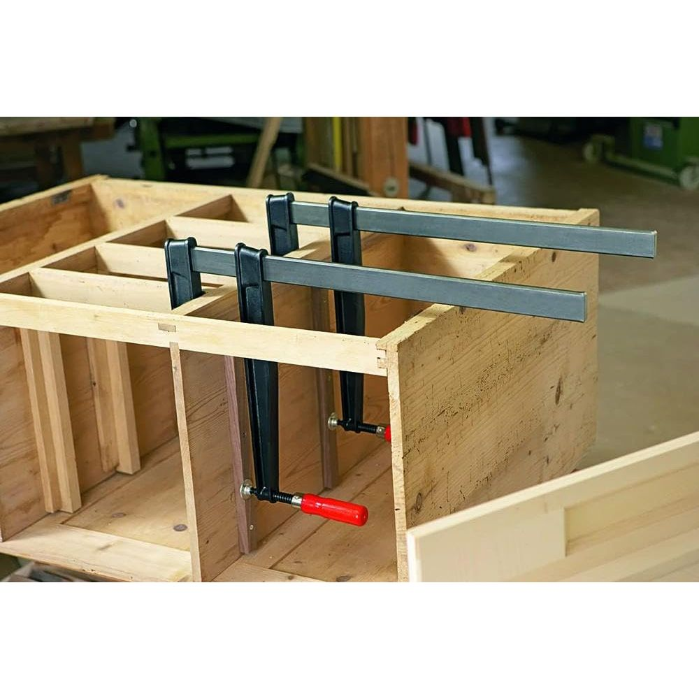 Zwei Holzzwingen mit roten Griffen sichern eine Holzkiste.