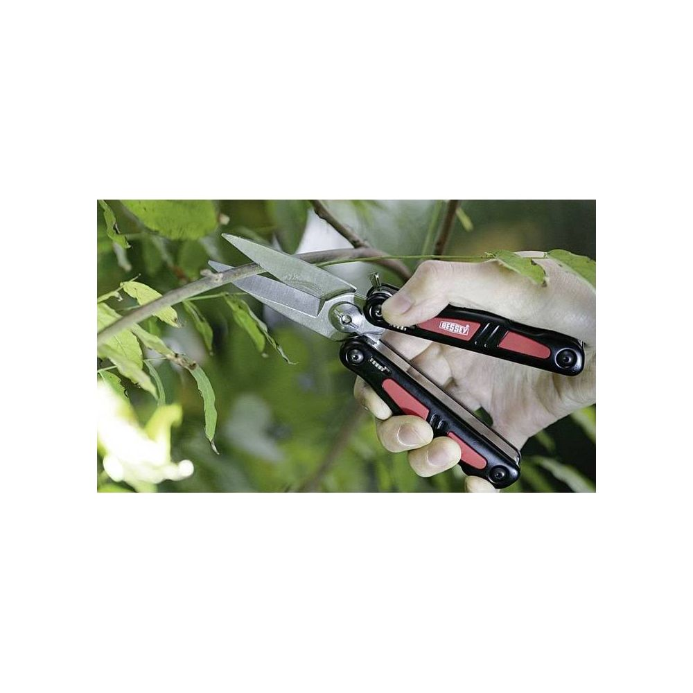 Una mano usa cesoie da giardino per tagliare un ramo, con fogliame verde.