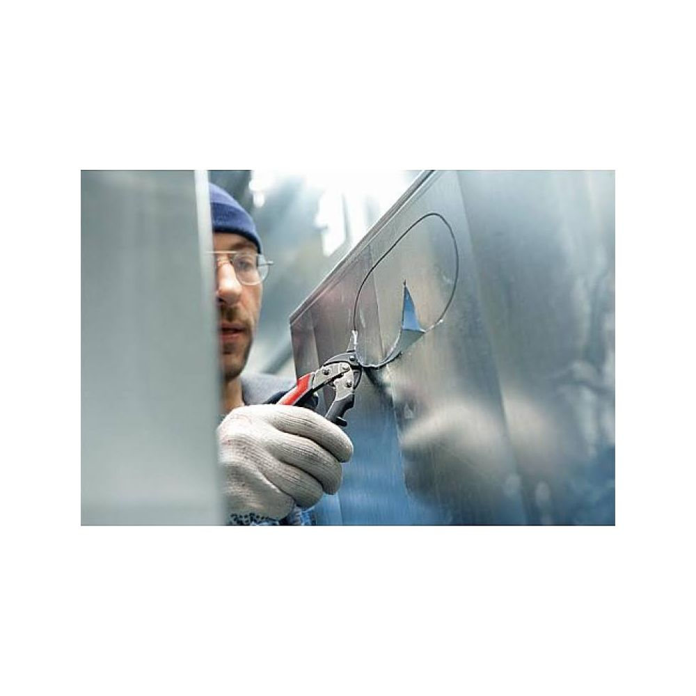 Ein Mann mit Mütze und Brille schneidet mit einer Zange Metallblech.