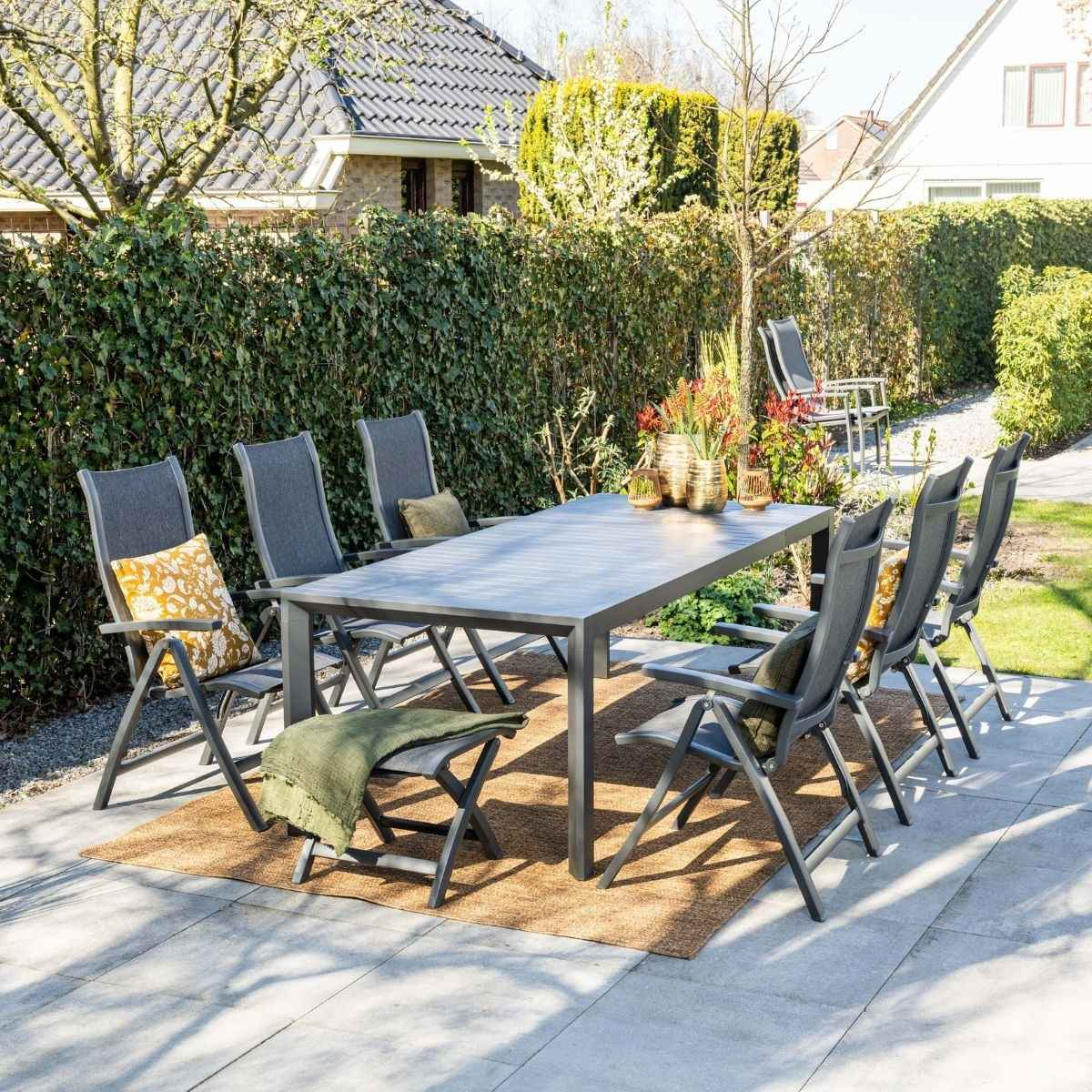 Een tuintafel met stoelen, kussens en een deken op een terras.