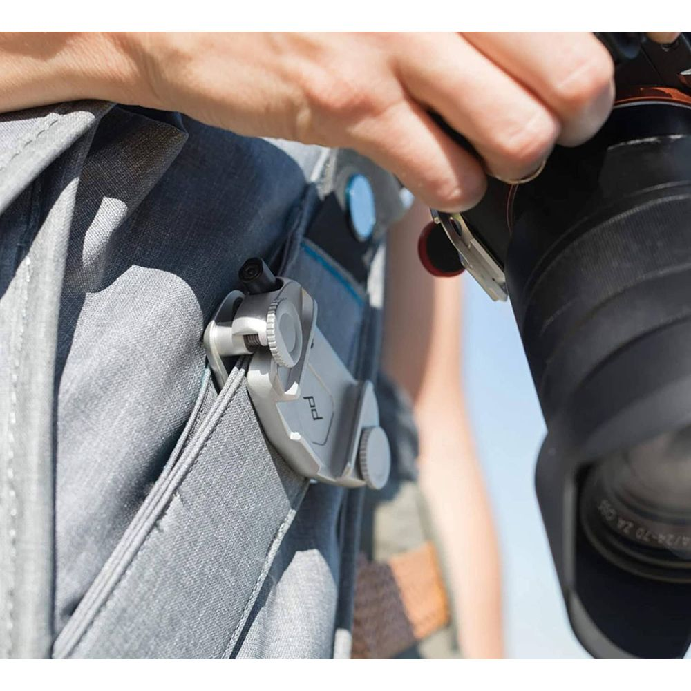 Zbliżenie dłoni trzymającej aparat przymocowany do plecaka.