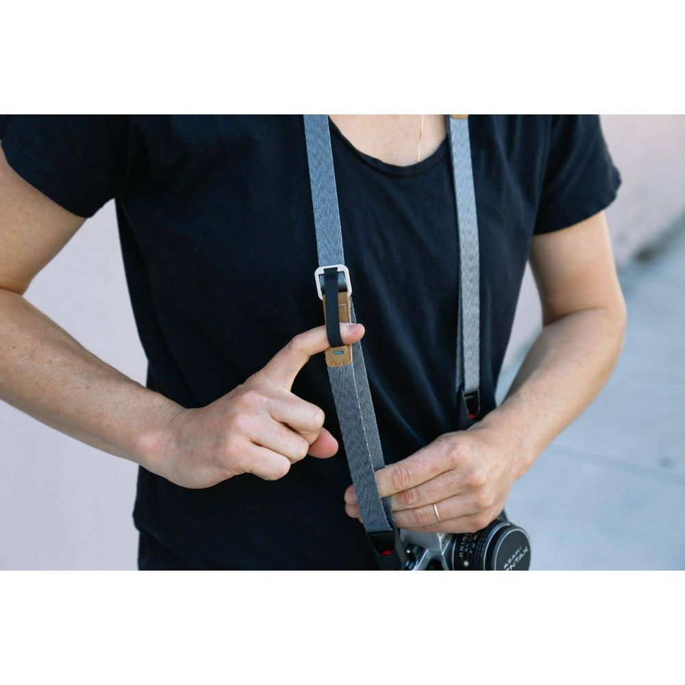 Personne en t-shirt noir ajuste la sangle de l'appareil photo.