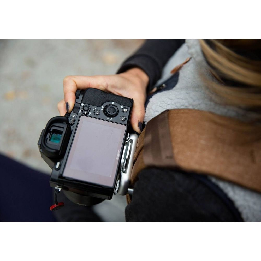 Una mano tiene una fotocamera Sony nera con schermo orientabile.