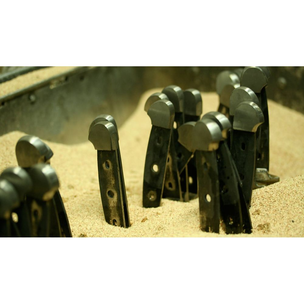 Messergriffe mit Metallkappen stecken in hellem Sand.
