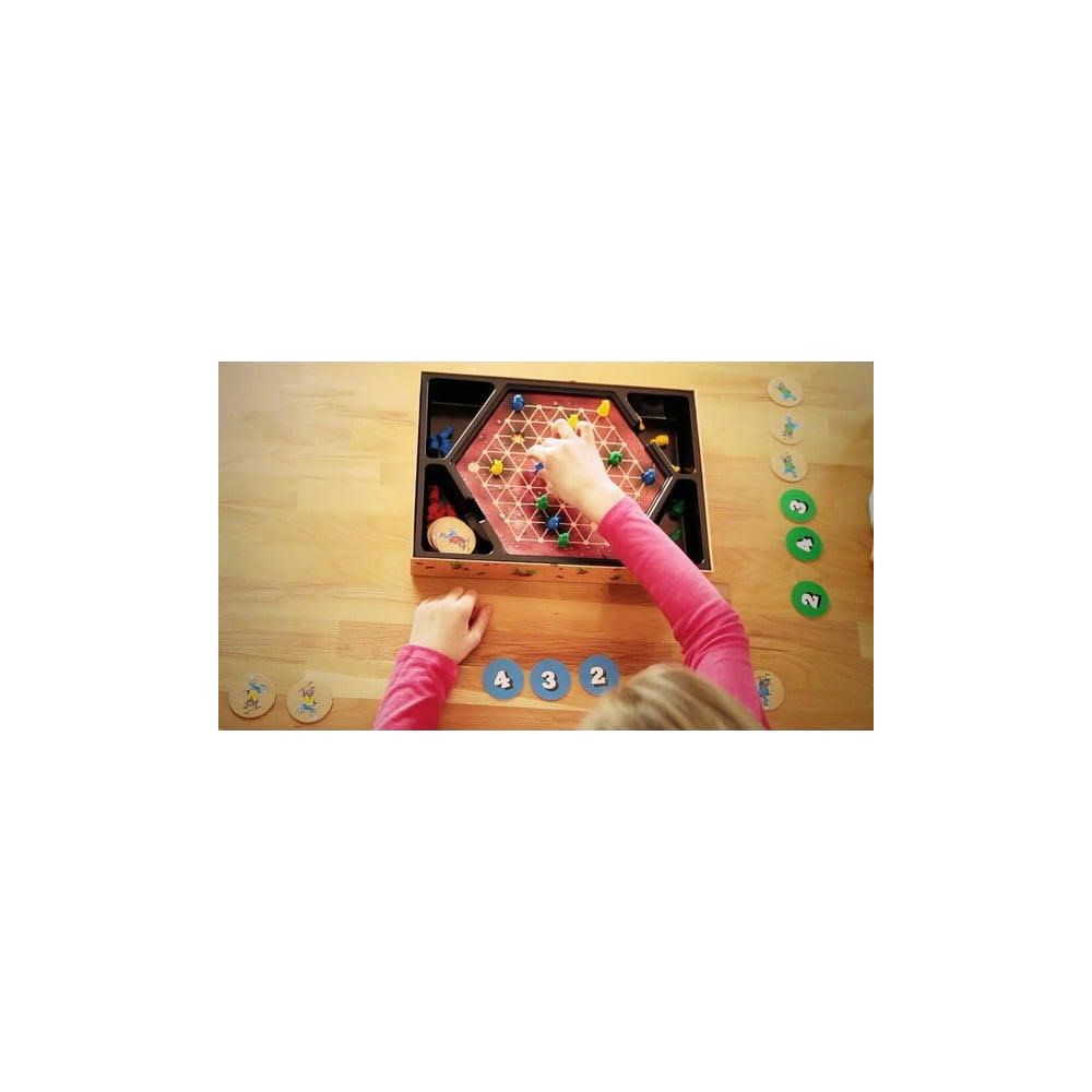 Un bambino gioca a un gioco da tavolo con pedine colorate su una tavola esagonale.