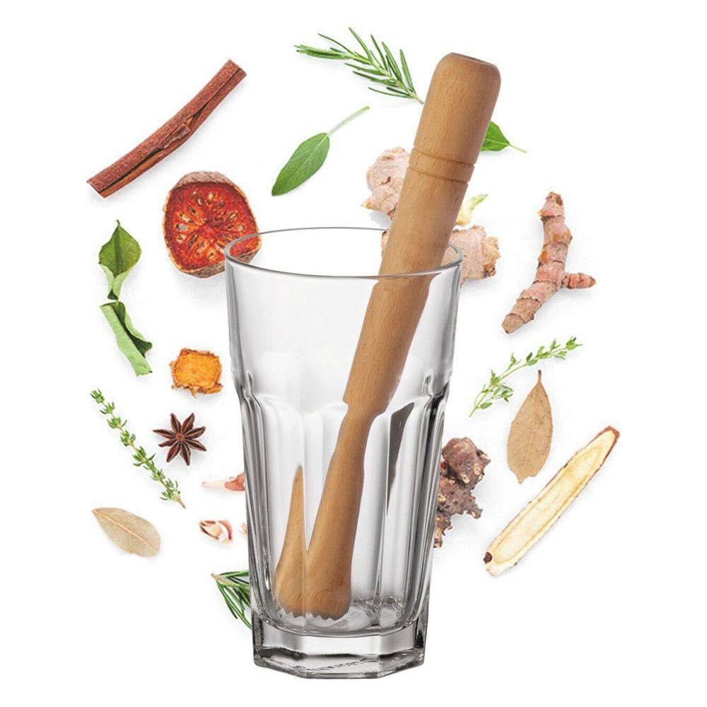 Ein Glas mit einem Holzstößel und Kräutern wie Zimt, Ingwer und Lorbeerblättern.