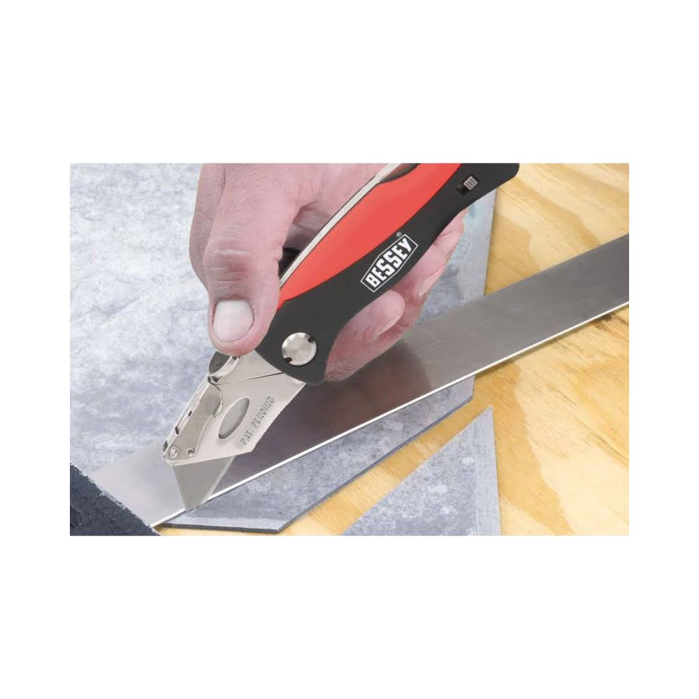 Ręka trzyma nóż i przecina metal na drewnianym stole.