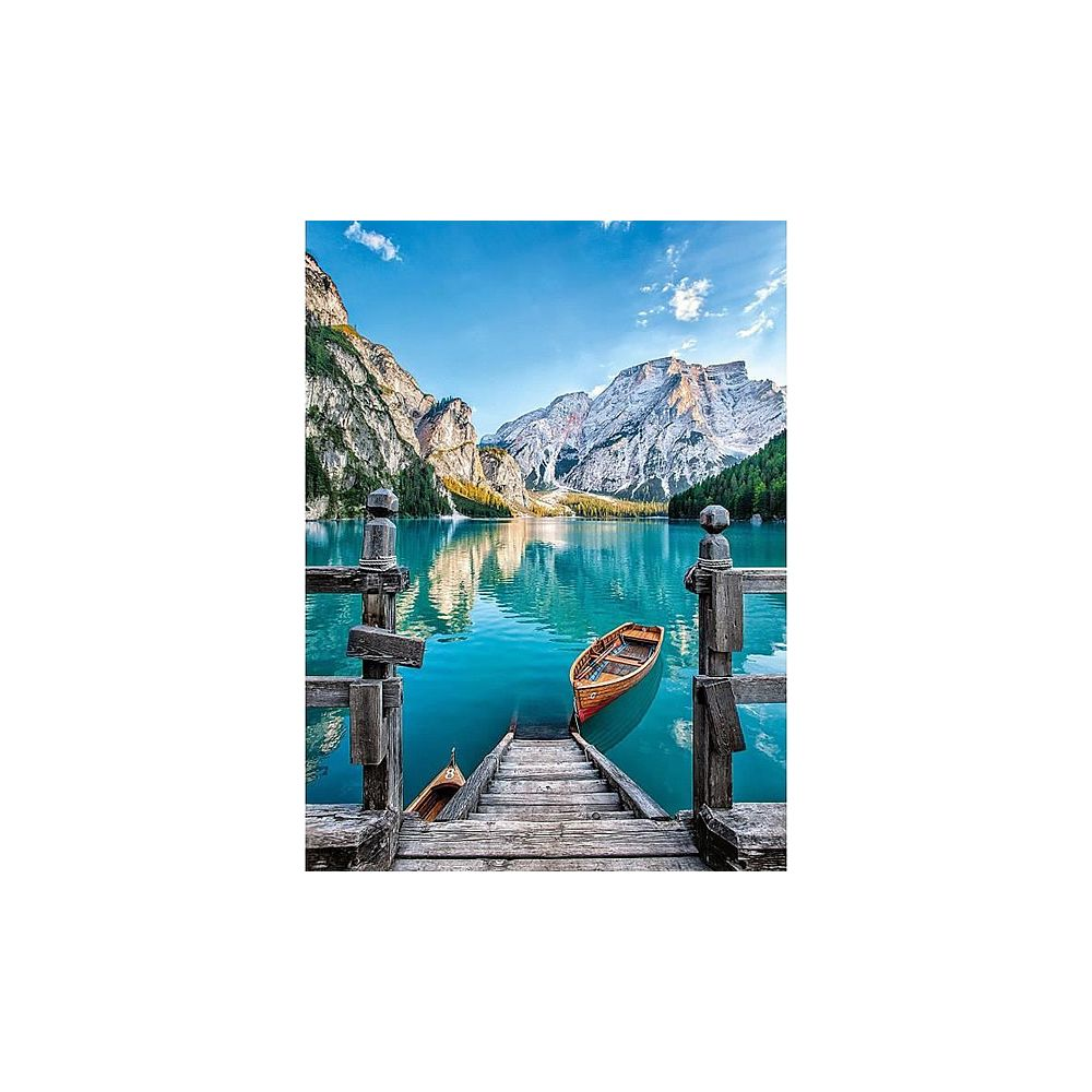 Drewniane molo prowadzi do turkusowego jeziora z górami w tle.