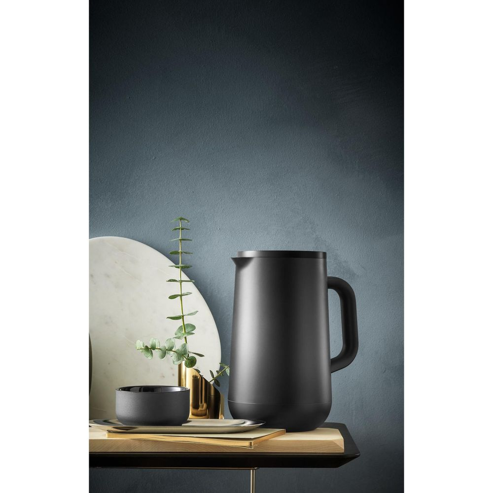Verseuse isotherme noire avec anse, bol et vase avec plante.