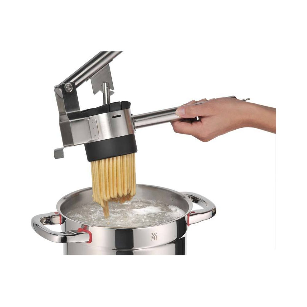 Eine Hand hält eine Nudelmaschine über einem Topf mit kochendem Wasser.