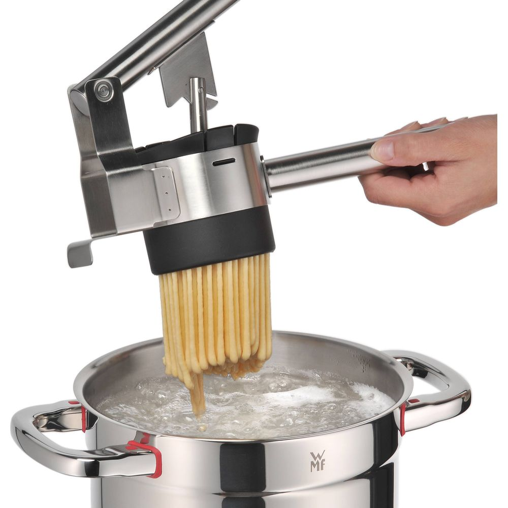 Eine Hand benutzt eine Nudelpresse, um Spaghetti in kochendes Wasser zu geben.