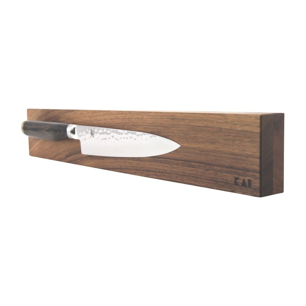 Ein Küchenmesser mit Hammerschlagmuster auf einem Holzblock. KAI-Logo sichtbar.