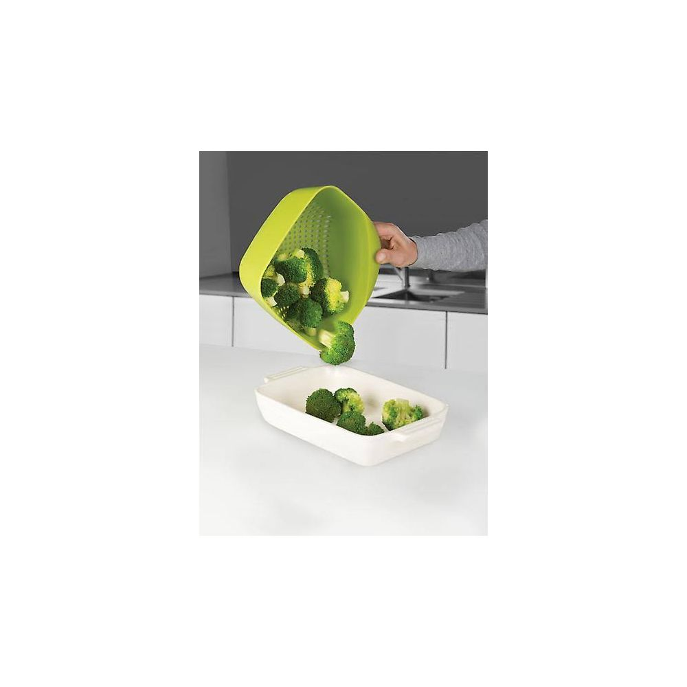 El brócoli cae de un colador verde a un plato blanco.