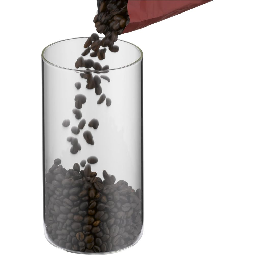 Kaffeebohnen fallen aus einer roten Verpackung in ein Glas.